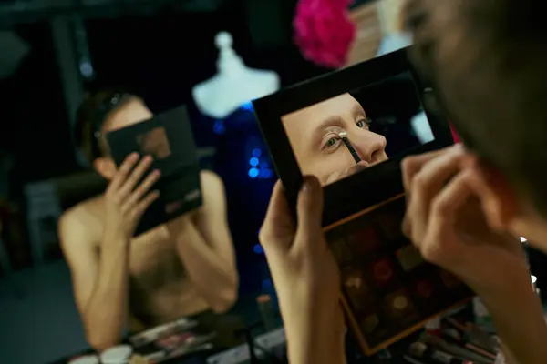 A drag queen applies eyeliner backstage, focusing on her reflection in the mirror. — Stock Photo