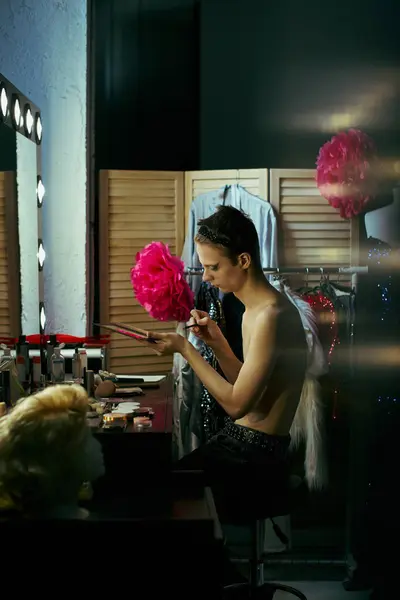A drag performer applies makeup while sitting at a dressing table, preparing for a performance. — Stock Photo