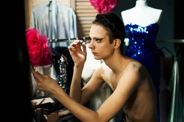 A drag performer applies makeup while looking in a mirror, preparing for a performance. — Stock Photo