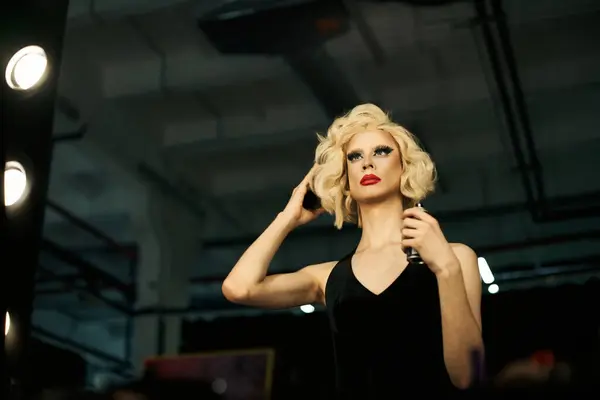 A drag queen adjusts their hair and makeup, preparing for a performance in a backstage dressing room. — Stock Photo