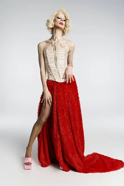 A drag queen in a red skirt and corset poses against a grey background. — Stock Photo