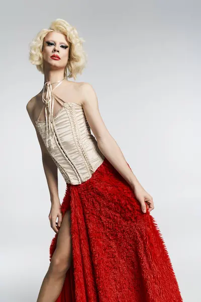 A drag queen with a blonde wig, red skirt, and corset poses against a grey background. — Stock Photo