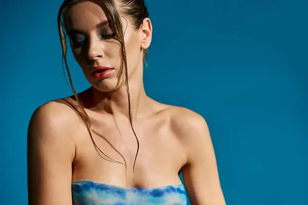 Una joven con un top de moda, su cabello mojado cayendo en cascada por sus hombros. - foto de stock