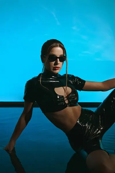 A young woman in black latex clothing poses with a seductive expression on a blue background. — Stock Photo