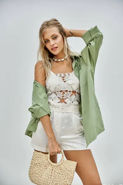 A blonde woman in stylish white beachwear poses against a grey background, showcasing summer fashion and trends. — Stock Photo