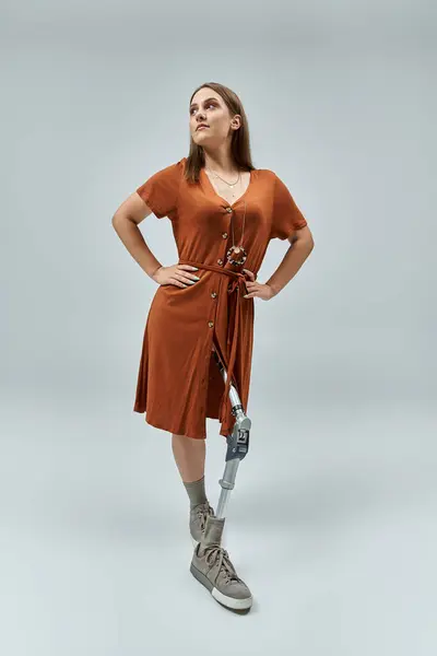 A woman in a rust-colored dress stands confidently, her prosthetic leg a symbol of resilience. — Stock Photo
