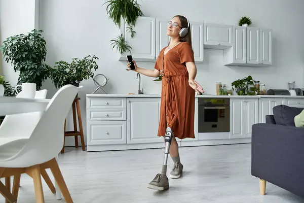 A woman with a prosthetic leg dances freely in her kitchen, enjoying the music. — Stock Photo