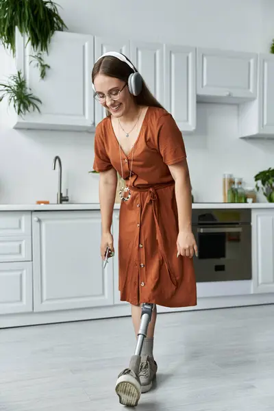 A woman with a prosthetic leg smiles while standing in a kitchen. — Stock Photo