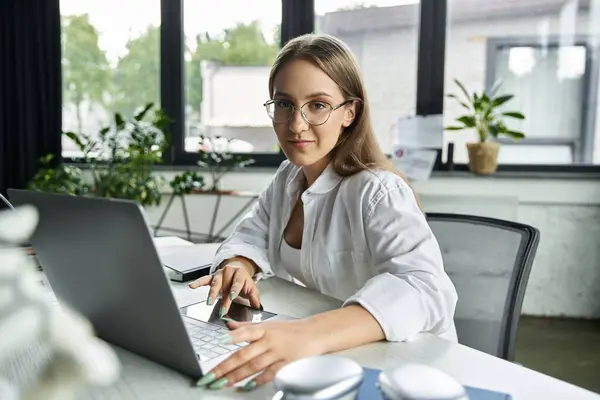 Una donna lavora su un computer portatile in un ufficio luminoso e moderno. — Foto stock