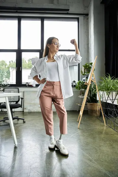 Woman with prosthetic leg in modern loft, wearing white shirt and pink pants, exudes confidence — Stock Photo