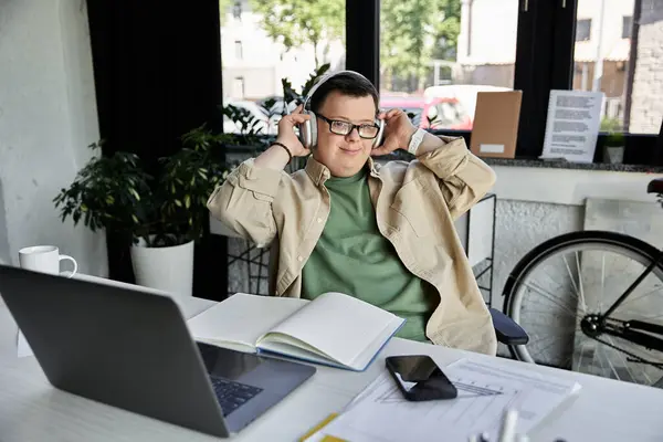 Молодий чоловік з синдромом Дауна відпочиває у своєму офісі з навушниками, насолоджуючись музикою. — стокове фото