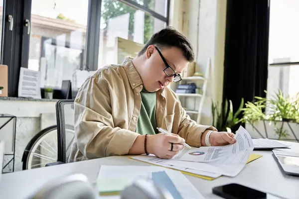A man with Down syndrome reviews documents in office, writin notes — Stock Photo