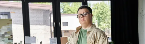 A young man with Down syndrome gazes out a window. — Stock Photo
