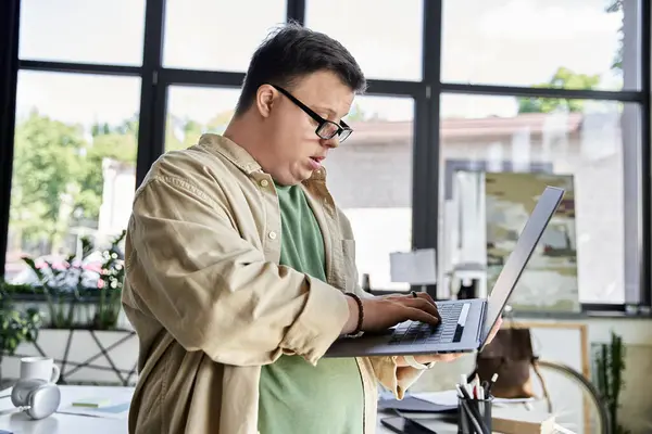 Um jovem com síndrome de Down usa um laptop em um ambiente de escritório. — Stock Photo