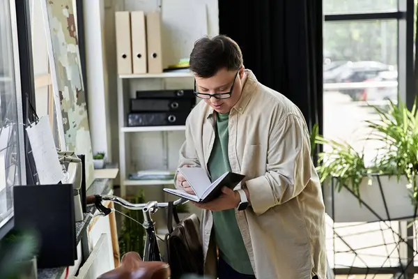Young man with Down syndrome reviewing notes while standing near a bicycle. — Stock Photo
