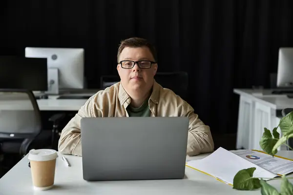 Junger Mann mit Down-Syndrom blickt während der Arbeit am Laptop in die Kamera — Stockfoto