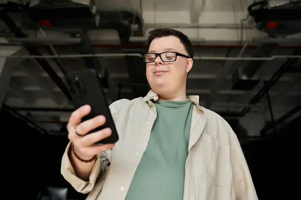 A man with Down syndrome looks at his phone, smiling. — Stock Photo