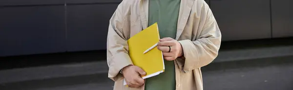 A man with Down syndrome holds a notebook and pen, standing confidently outside. — Stock Photo