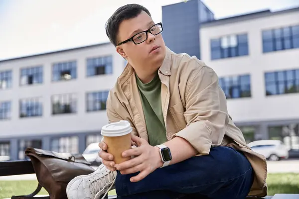Um homem com síndrome de Down senta-se em um banco, segurando cuidadosamente uma xícara de café. — Fotografia de Stock
