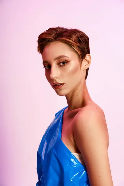 Una mujer con el pelo castaño corto posa en un vestido de moda azul y sostenible. - foto de stock