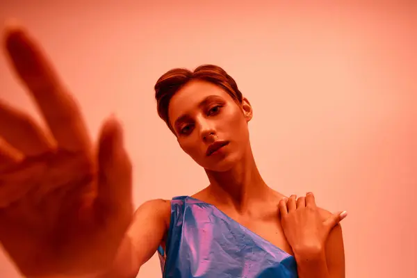 A woman in a blue dress reaches out her hand, her expression both confident and alluring. — Stock Photo