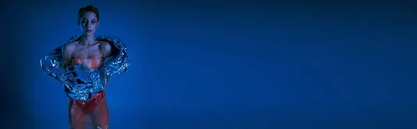 A woman in red and silver clothing poses against a blue background. — Stock Photo