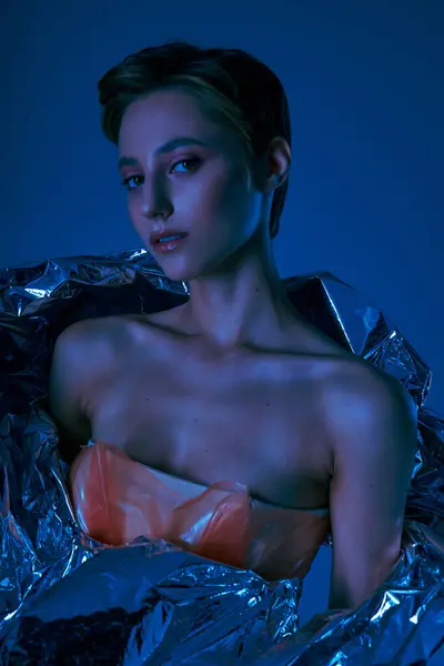 A woman in a silver garment poses against a dark blue background. — Stock Photo