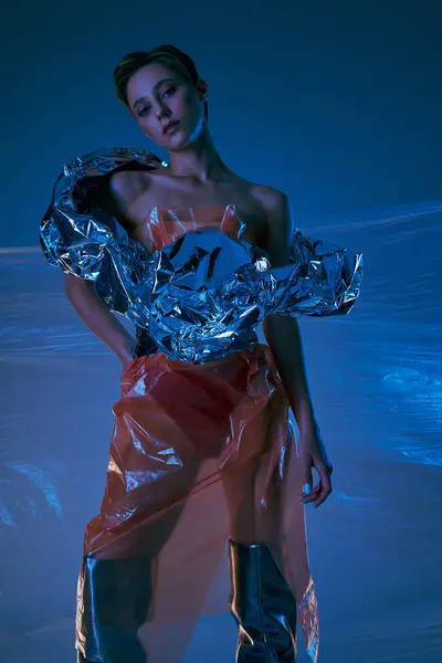 A woman in a silver and red outfit stands against a blue backdrop. — Stock Photo