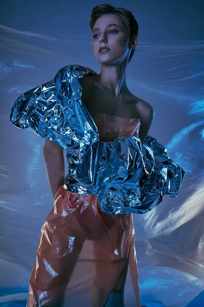 A woman in a sustainable fashion design poses in a dreamlike, blue setting. — Stock Photo