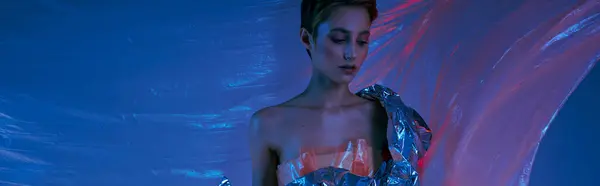 Uma mulher em uma roupa de prata está contra um pano de fundo de luz azul e vermelha. — Fotografia de Stock