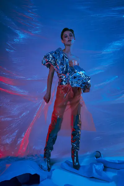 Femme en studio coloré portant le dessus d'argent et des bottes noires parmi le plastique tourbillonnant — Photo de stock