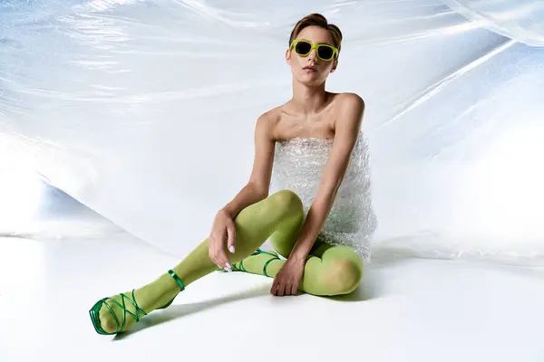 Uma mulher vestindo meias verdes e um plástico bolha envoltório vestido posa em um fundo branco. — Fotografia de Stock