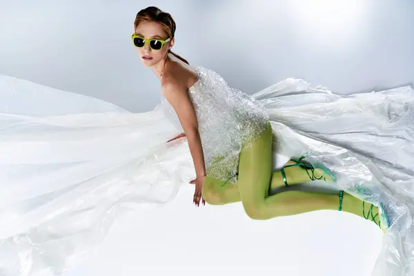 Uma mulher de meia-calça verde posa dramaticamente contra um pano de fundo de tecido branco. — Fotografia de Stock