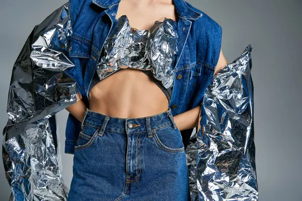 A woman poses in a denim jacket and skirt, accented with shimmering silver fabric. — Stock Photo