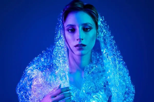 Une femme dans une pièce de mode durable, baignée de lumière au néon bleu et violet. — Photo de stock