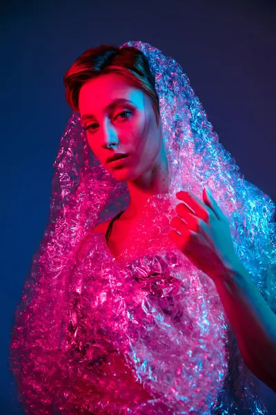 A woman poses in a studio with colorful lights, wrapped in bubble wrap. — Stock Photo
