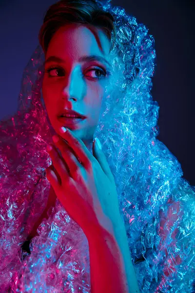 A woman's face is illuminated by red and blue light, as she is wrapped in plastic. — Stock Photo