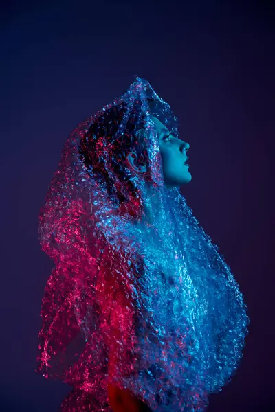 Woman in neon-lit room, head tilted back, wrapped in bubble wrap — Stock Photo