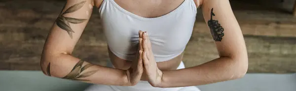 A young woman in active wear meditates in a modern apartment, focusing on inner peace and mindfulness. — Stock Photo