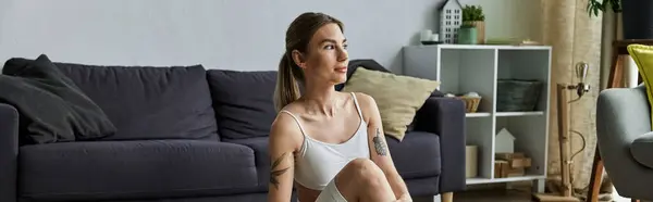 Una joven con vitiligo se sienta en una pose de yoga en su apartamento moderno, practicando meditación y centrándose en su salud mental. - foto de stock