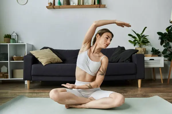 A young woman with vitiligo practices yoga on a mat in her modern apartment. — Stock Photo