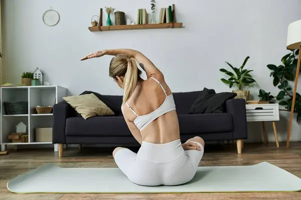 Eine junge Frau in aktiver Kleidung praktiziert Yoga in ihrer Wohnung und konzentriert sich auf Meditation und geistiges Wohlbefinden. — Stockfoto