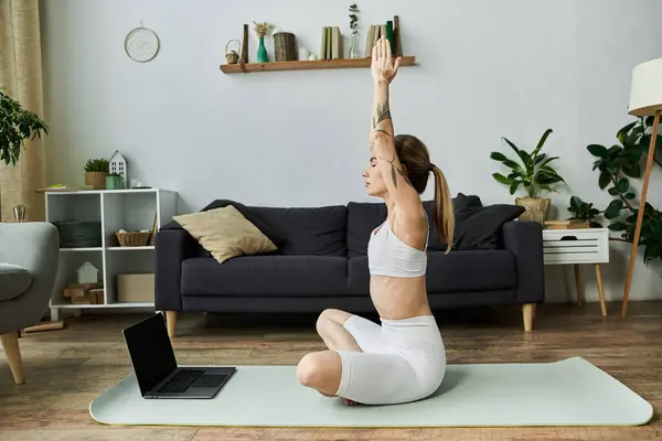 Eine junge Frau mit Vitiligo praktiziert Yoga in einer modernen Wohnung, die Arme in friedlicher Pose auf einer hellgrünen Matte erhoben. — Stockfoto