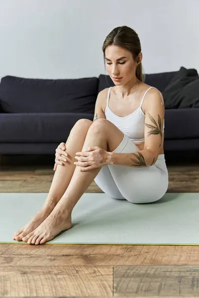 A young woman with vitiligo meditates on a yoga mat in a modern apartment. — Stock Photo