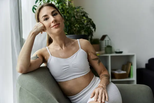 A young woman with vitiligo sits on a couch in a modern apartment, reflecting on her practice. — Stock Photo