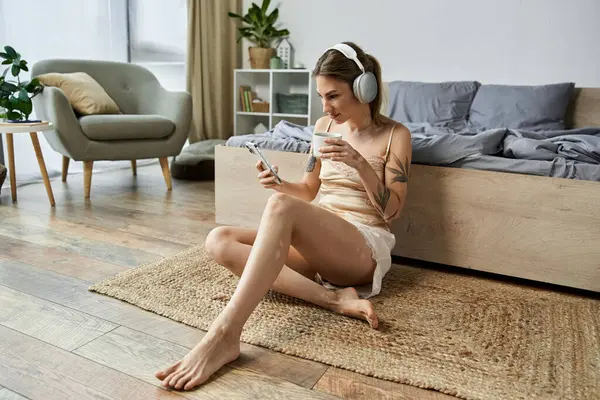 A young woman with vitiligo and a tattoo relaxes in her cozy bedroom, listening to music and enjoying a cup of coffee. — Stock Photo