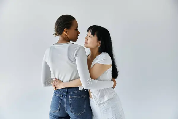 A young African American woman embraces her Asian girlfriend, their eyes locked in a tender gaze. — Stock Photo