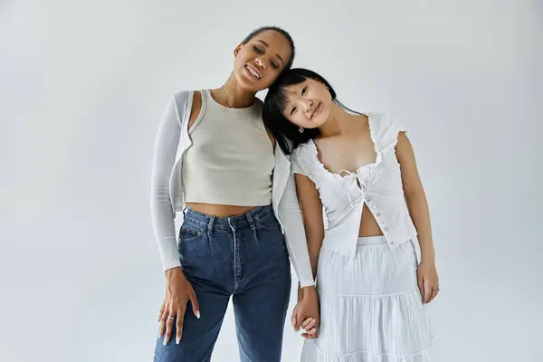 Two young women, one African American and other Asian, stand close together, their foreheads touching, in a tender moment. — Stock Photo