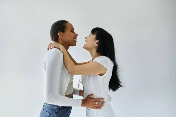 An interracial lesbian couple shares a tender moment, their laughter echoing in the quiet studio. — Stock Photo