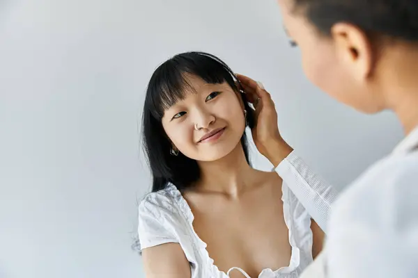 Eine junge Asiatin lächelt, als ihr Partner, eine Afroamerikanerin, ihr sanft über die Haare streicht. — Stockfoto